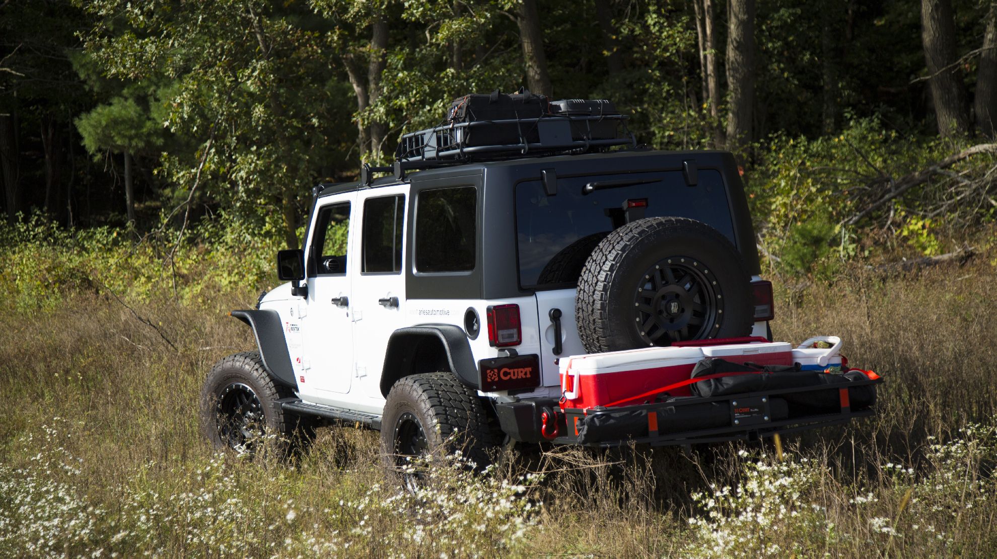 Jeep in a grassy field with a hitch mounted cargo basket
