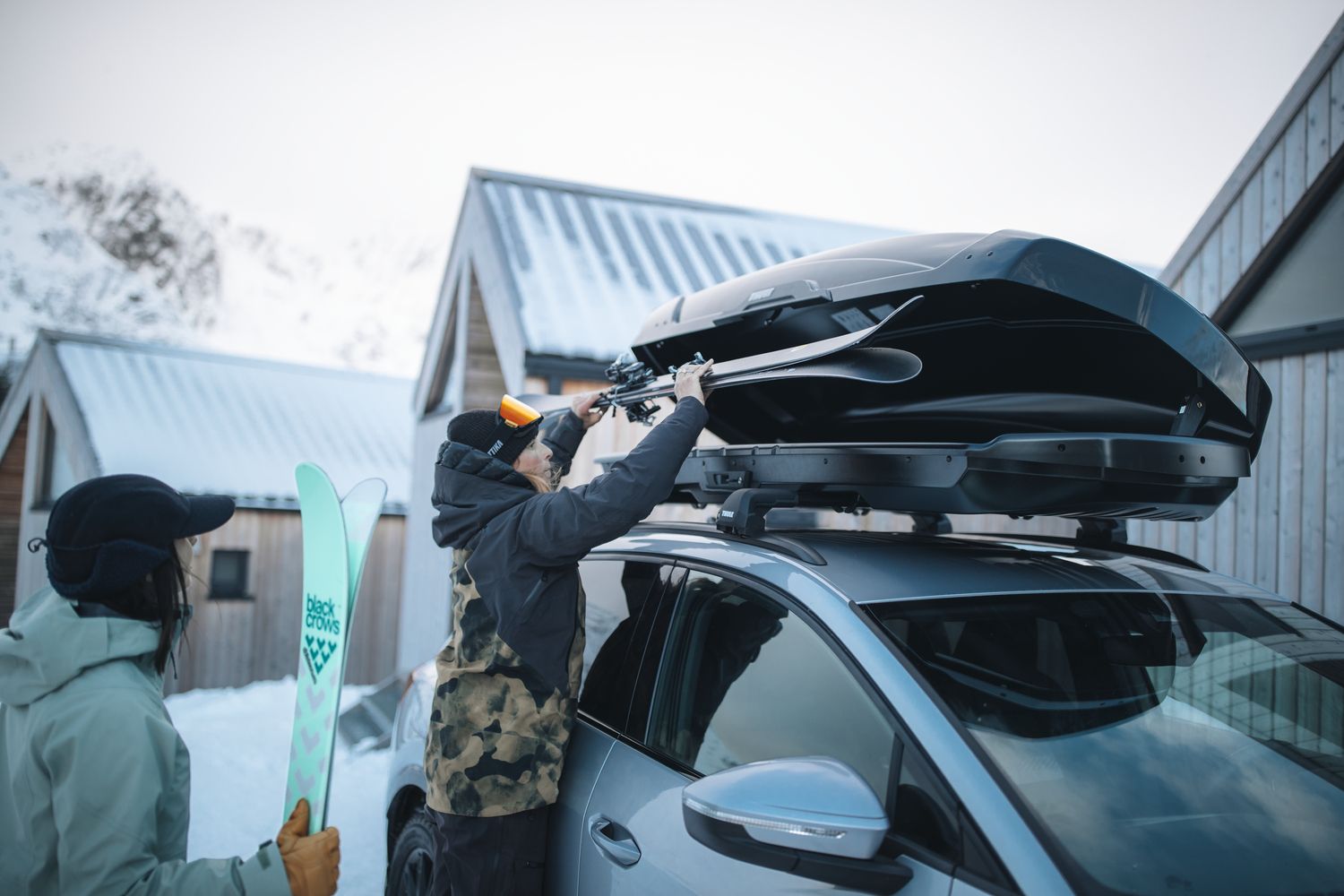 skis and snowboards being loaded into a roof mounted cargo box