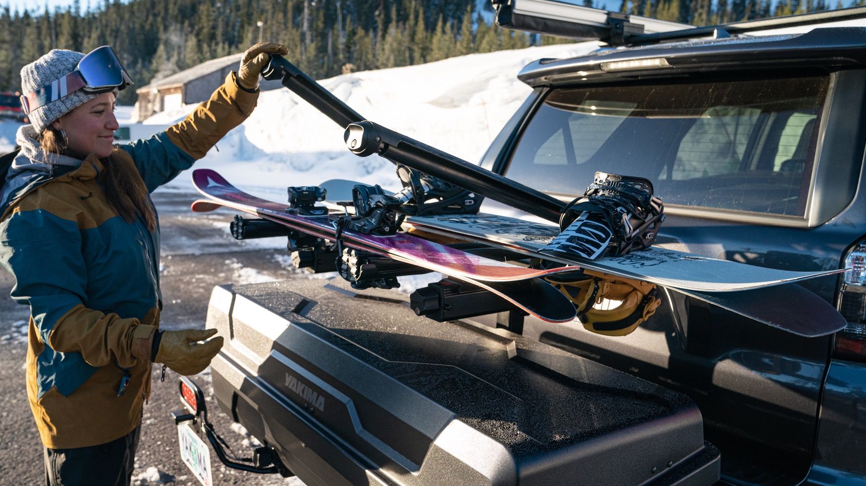Skis and snowboards being loaded onto a hitch mounted cargo carrier