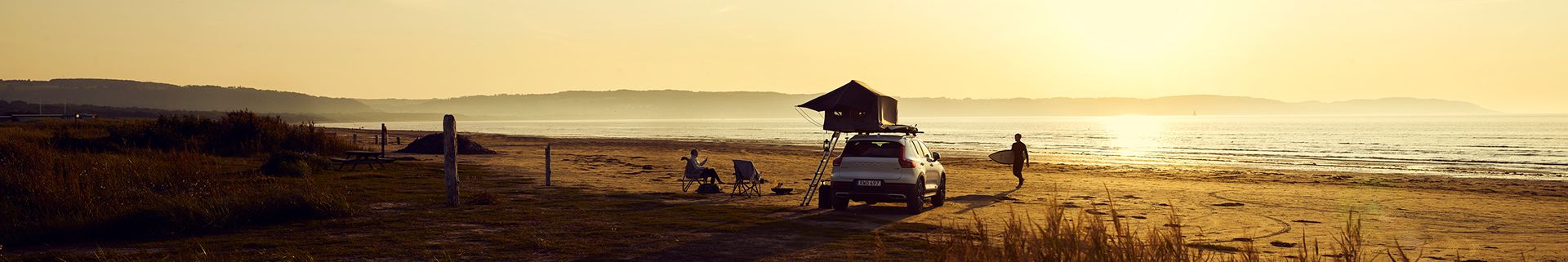 A beach camping scene with a car and a roof top tent